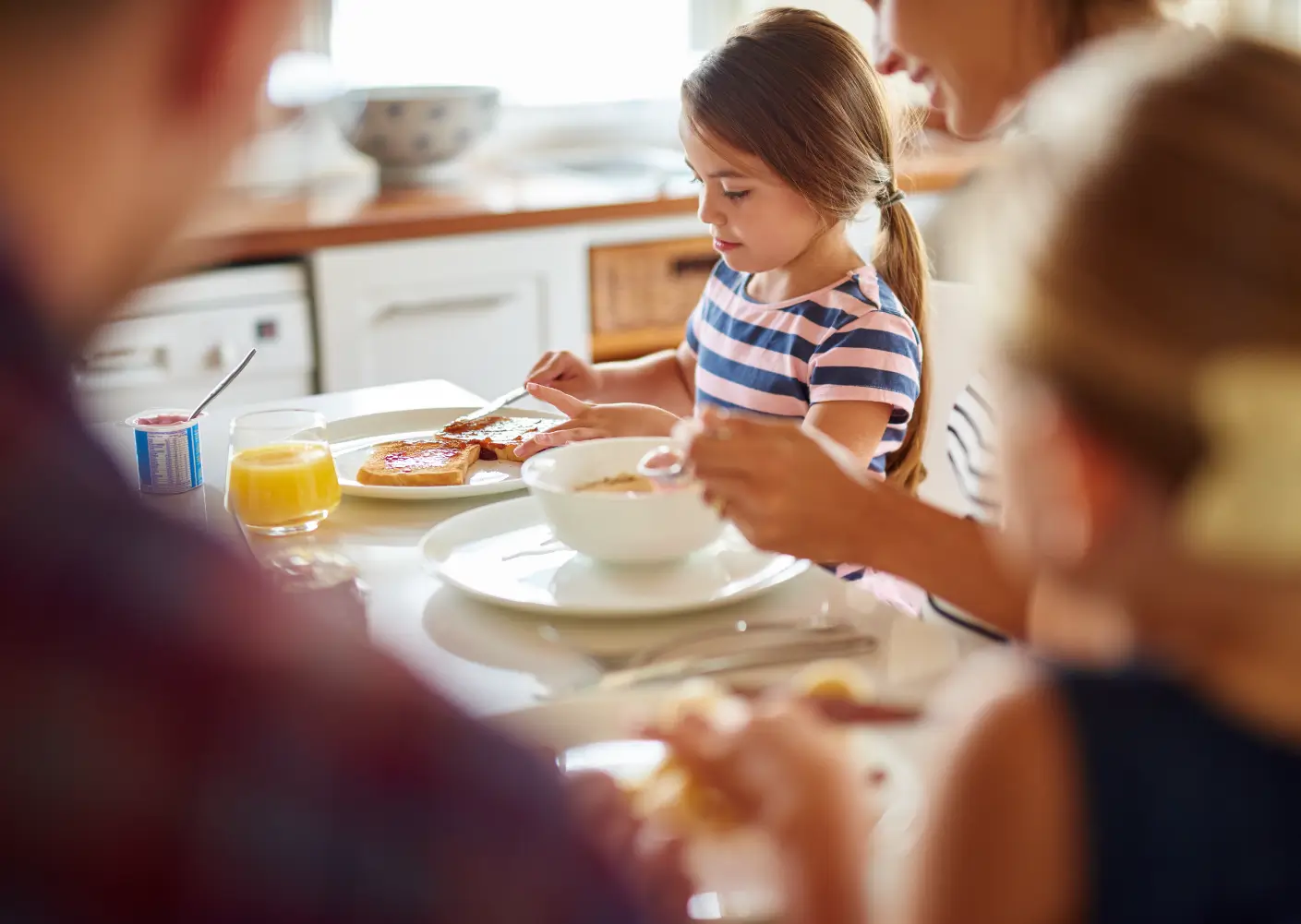 En flicka på 7 år som äter frukost med familjen som hon placerats hos