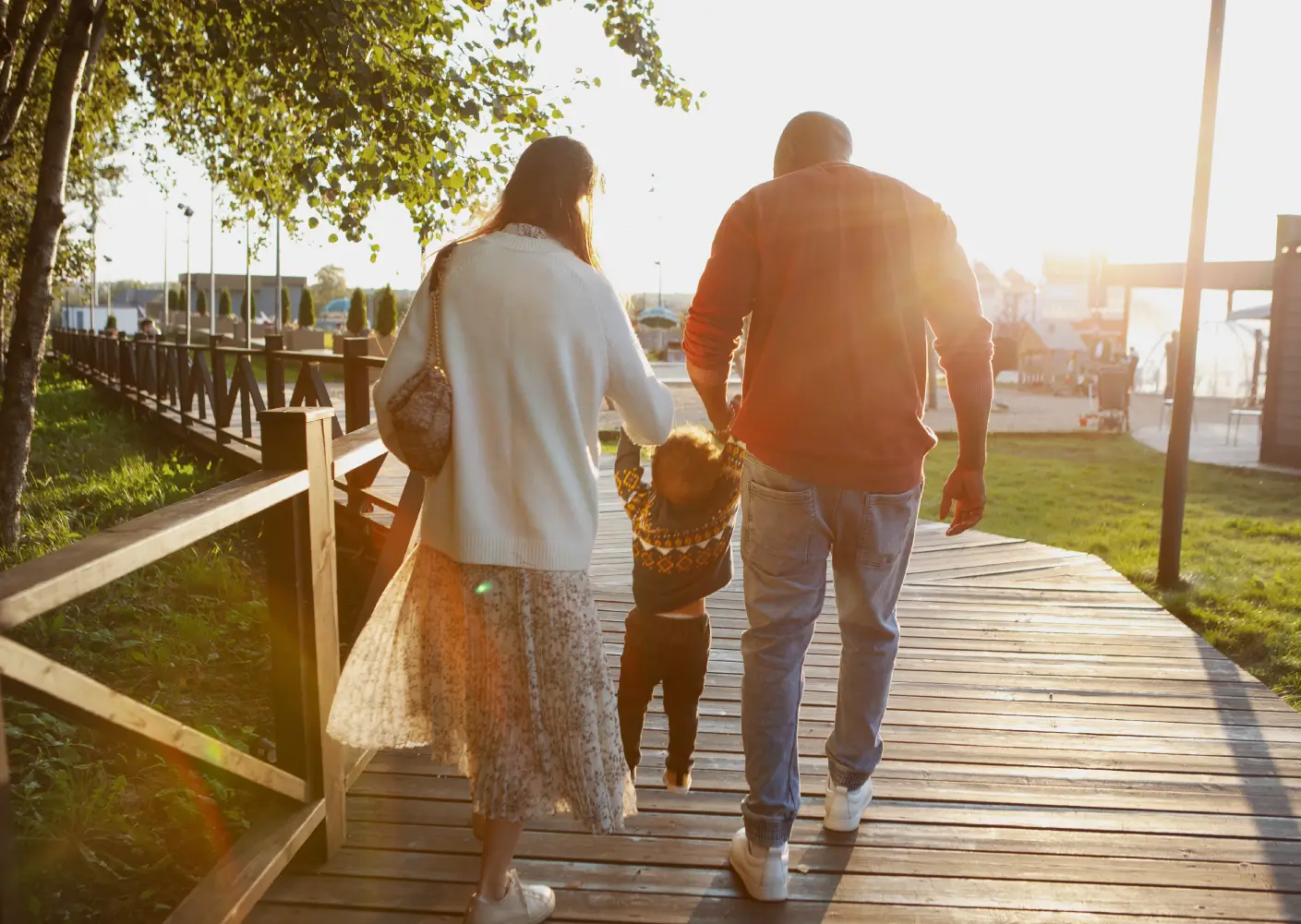 En man och en kvinna som går med ett barn som de lyfter upp i armarna på skoj