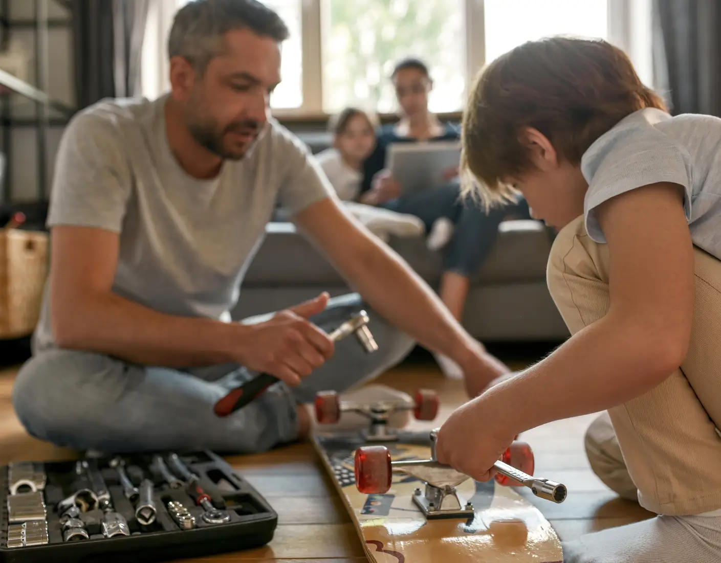 En medelålders man som meckar med en skateboard tillsammans med en pojke