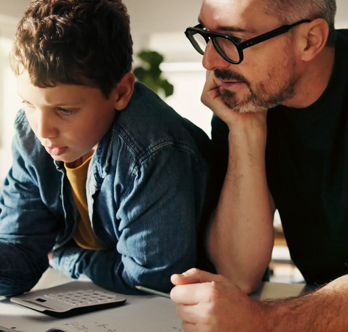 En medelålders man som hjälper en tonårspojke med läxor